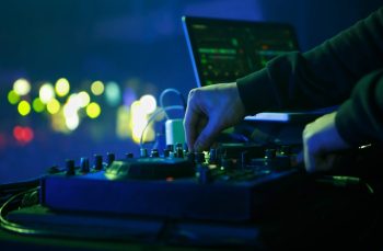 DJ playing electronic music set on party in night club. Close up photo of disc jockey mixing musical tracks with midi controller device
