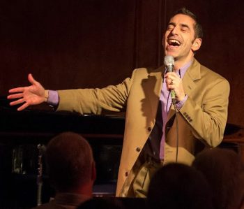 man (brian de lorenzo) singing on stage with a microphone.