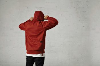 young-hipster-adjusts-hood-his-brownish-red-parka-back-view-portrait-studio-with-white-walls